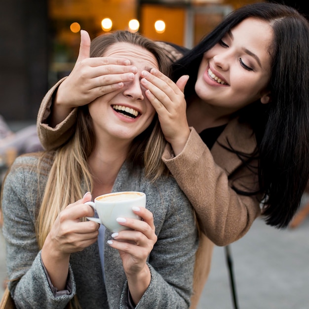 Free photo woman covering her friend's eyes