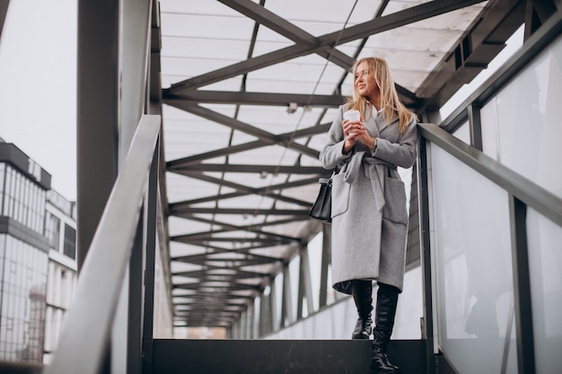 Woman crossing the bridge and drinking coffee