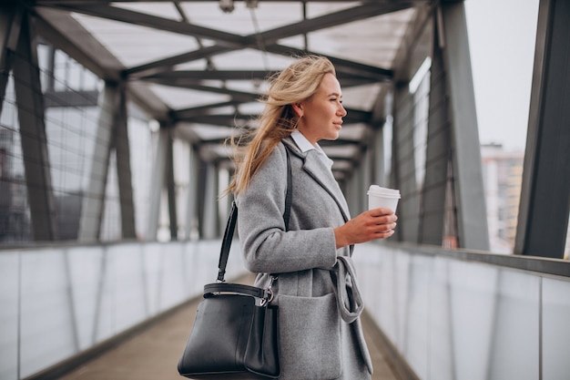 Woman crossing the bridge and drinking coffee