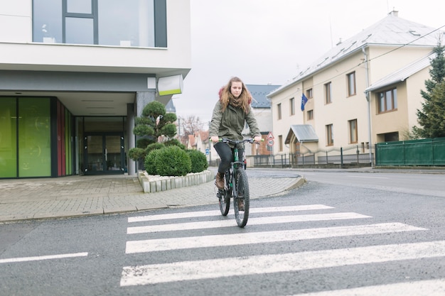 Free photo woman crossing street on bike