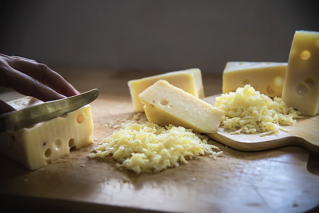 Woman cut slice cheese for cook using knife in the kitchen - people making food with cheese concept