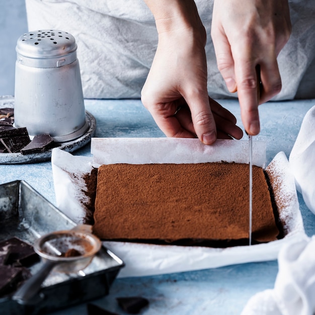 Free photo woman cutting chocolate ganache truffle squares in the kitchen