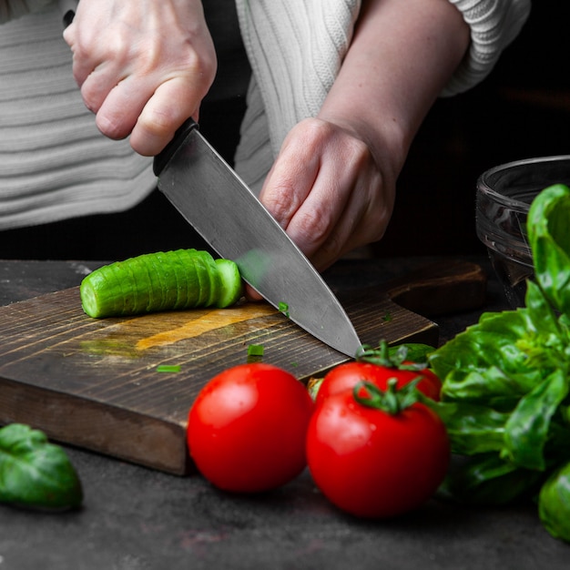 Free Photo woman cutting cucumber at table