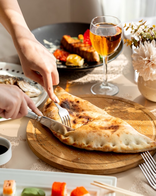 Woman cutting stuffed pie served on wooden board