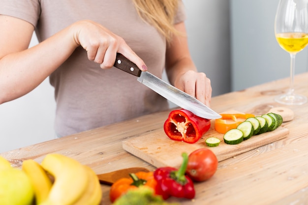 Free photo woman cutting vegetables on a wooden support