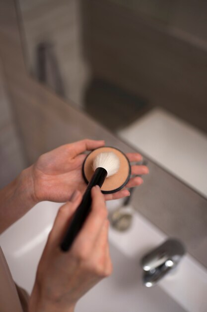 Woman dealing with rosacea applying make-up with brush