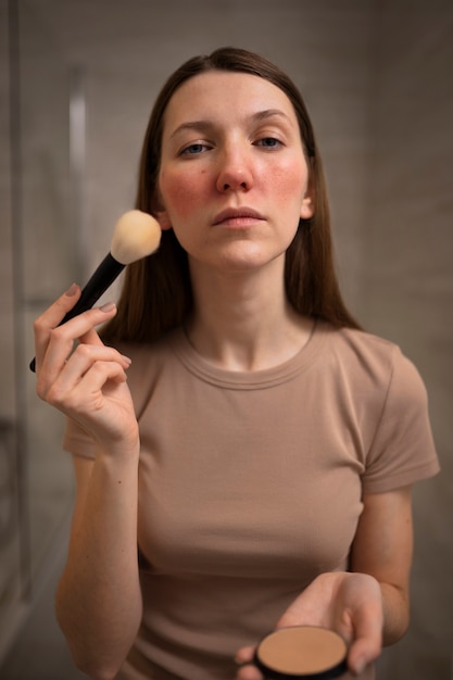 Woman dealing with rosacea applying make-up with brush