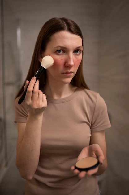 Woman dealing with rosacea applying make-up with brush