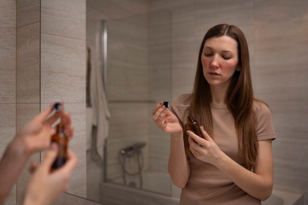 Woman dealing with rosacea using serum for skin