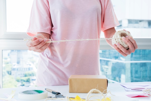 Free photo woman decorating the box with thread on table