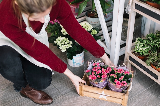 Woman decorating shop with box of flowers