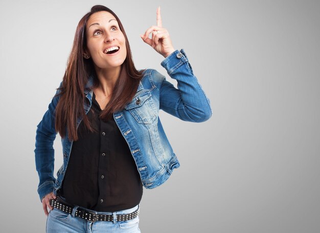 Woman in denim jacket pointing upwards