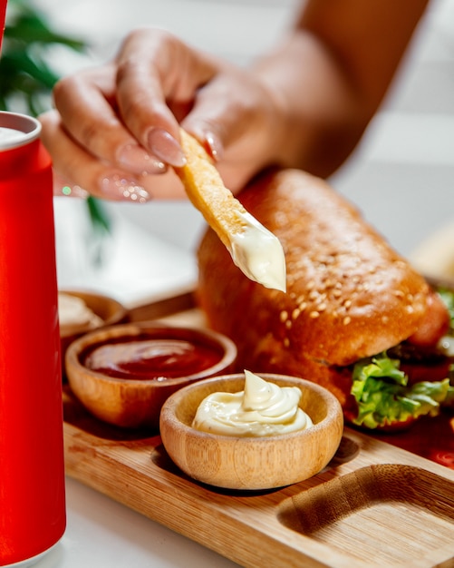 Woman dips fries into mayonnaise