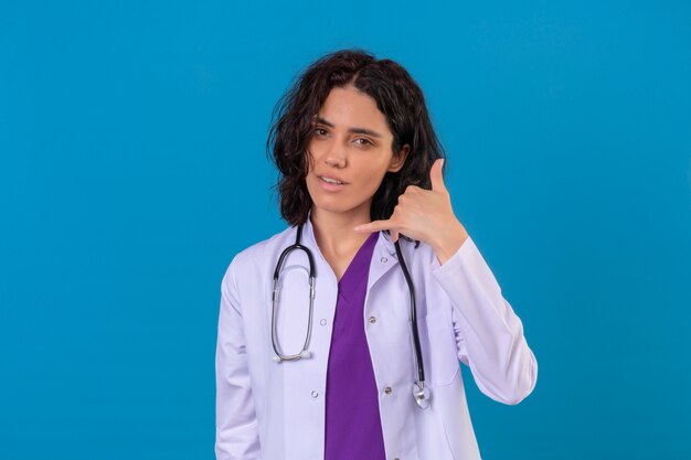 Free Photo woman doctor wearing white coat with stethoscope making call me gesture looking confident on isolated blue