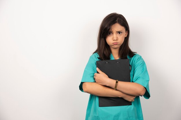 Woman doctor with clipboard holding her breath on white background. High quality photo