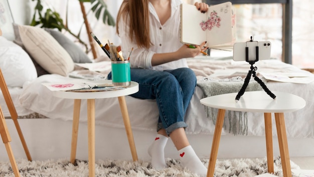 Woman doing a drawing tutorial with her phone at home