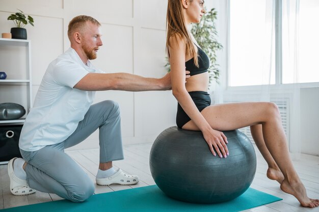 Woman doing exercises with ball and physiotherapist