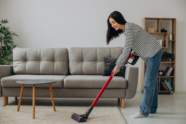 Woman doing house work with rechargeable vacuum cleaner