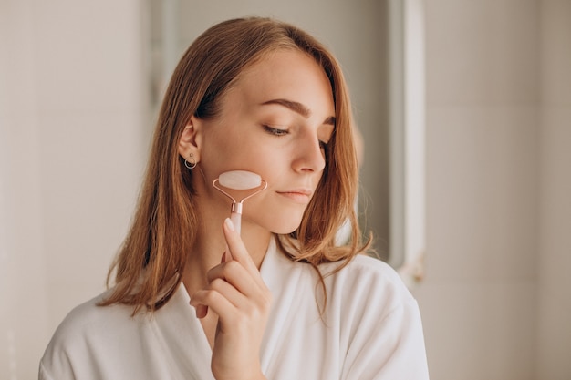 Woman doing self massage with rose quartz face roller