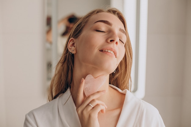 Woman doing self massage with rose quartz gua sha stone