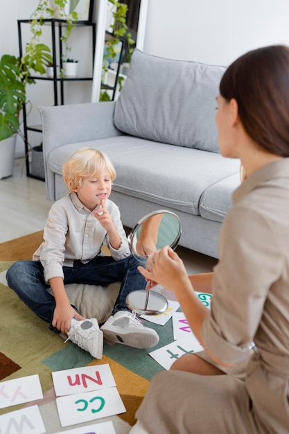 Free Photo woman doing speech therapy with a little blonde boy