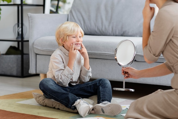 Free photo woman doing speech therapy with a little blonde boy