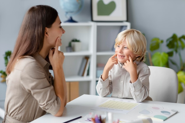 Free photo woman doing speech therapy with a little blonde boy