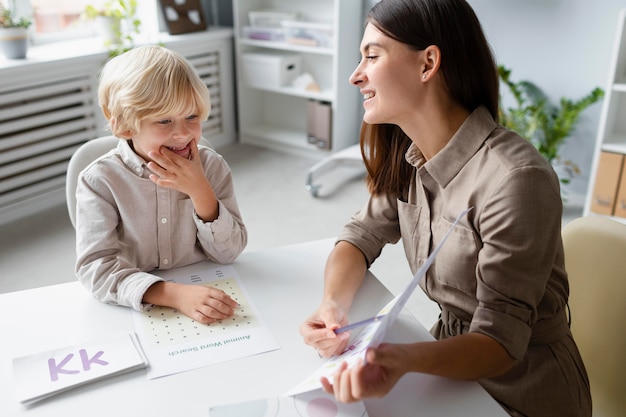 Free Photo woman doing speech therapy with a little blonde boy