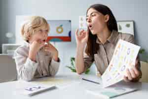 Free photo woman doing speech therapy with a little blonde boy