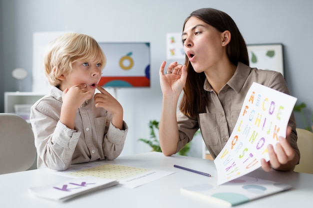 Free Photo woman doing speech therapy with a little blonde boy