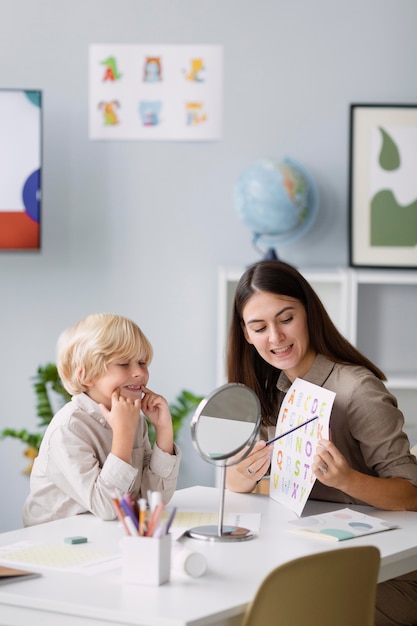 Free Photo woman doing speech therapy with a little boy at her clinic