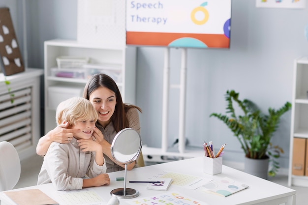 Woman doing speech therapy with a little boy at her clinic