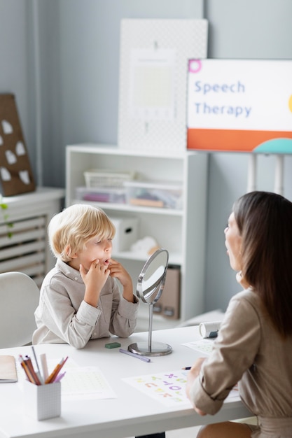 Woman doing speech therapy with a little boy at her clinic