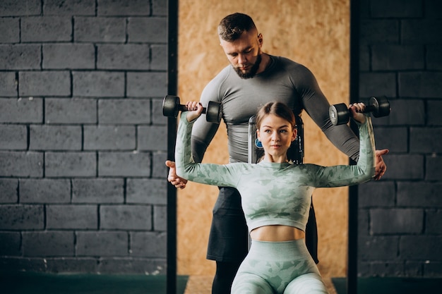 Free photo woman doing workout at the gym with trainer