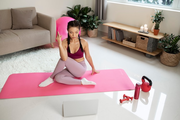 Woman doing yoga after online fitness instructor