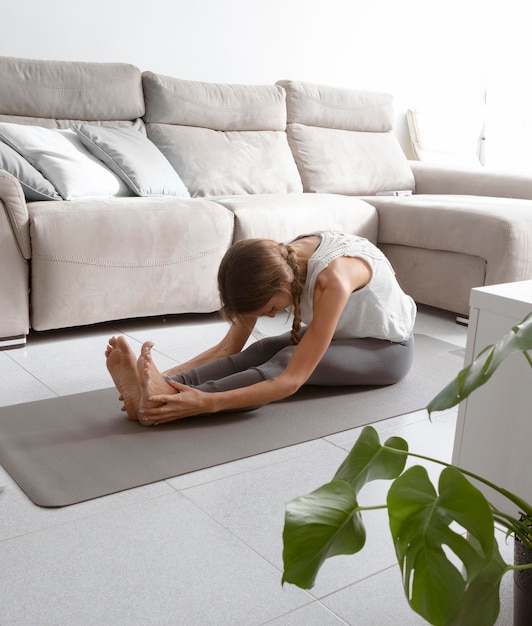 Free photo woman doing yoga at home on mat