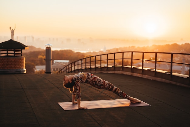 Free Photo woman doing yoga on the roof of a skyscraper in big city.