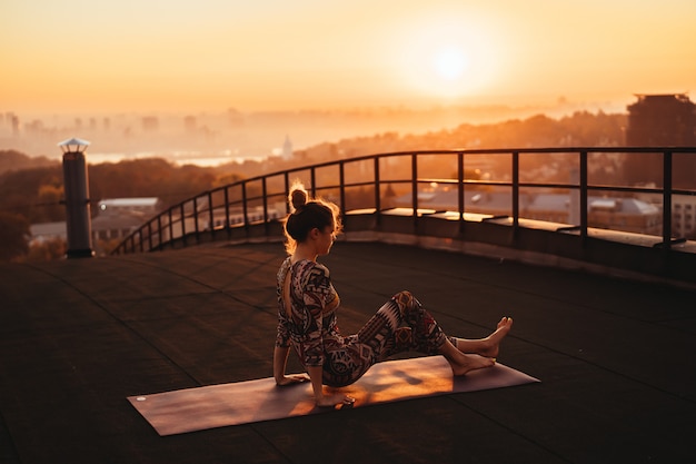 Woman doing yoga on the roof of a skyscraper in big city.