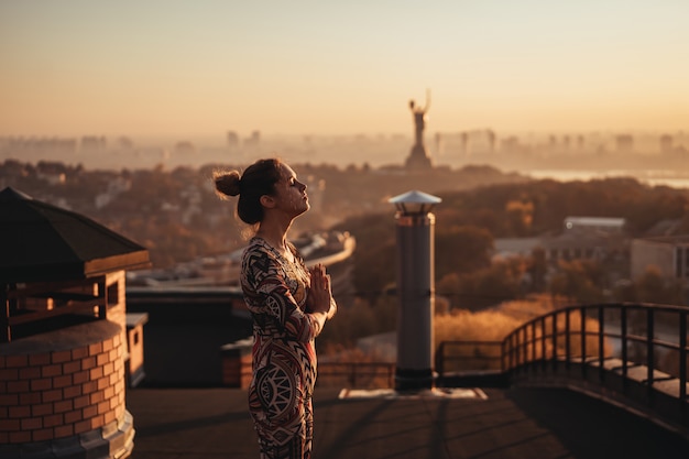 Woman doing yoga on the roof of a skyscraper in big city.