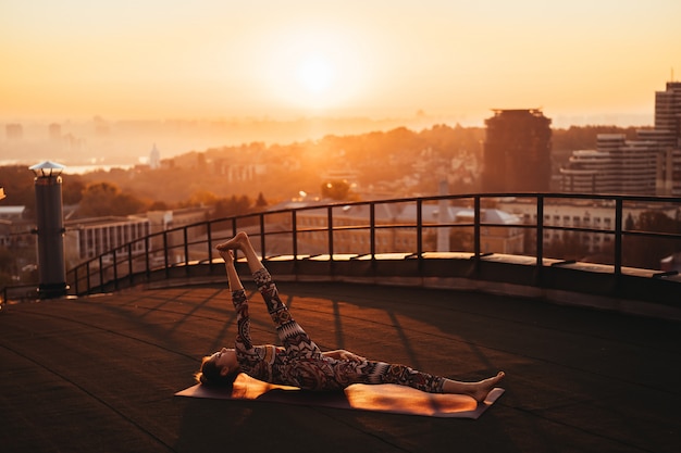 Free photo woman doing yoga on the roof of a skyscraper in big city