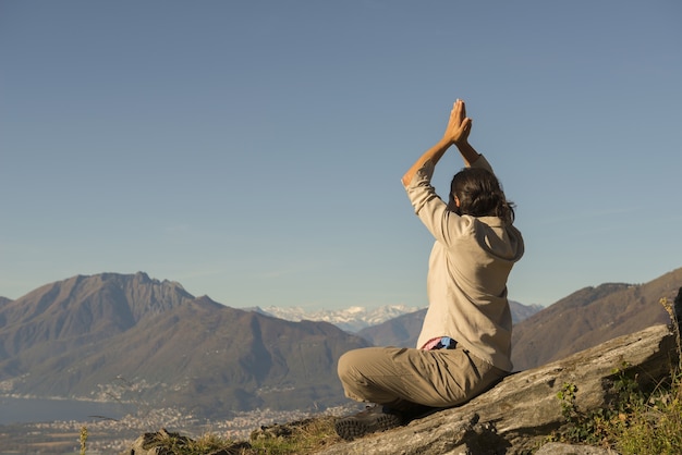 Free Photo woman doing yoga on the top of a mountain on a sunny day in switzerland