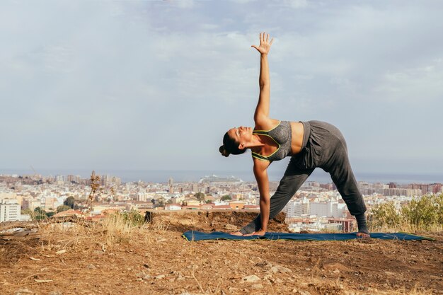 Woman doing yoga with the city at the background