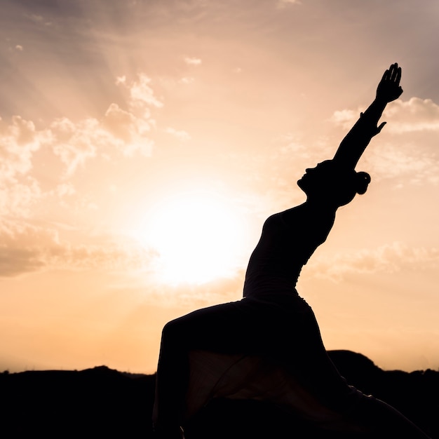 Woman doing yoga with the sunset