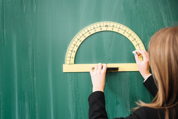 Free Photo woman drawing geometrical figure on blackboard