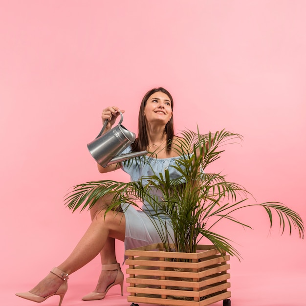 Woman in dress watering plant in pot