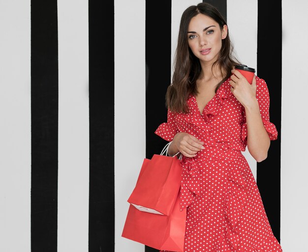 Woman in dress with coffee and shopping bags