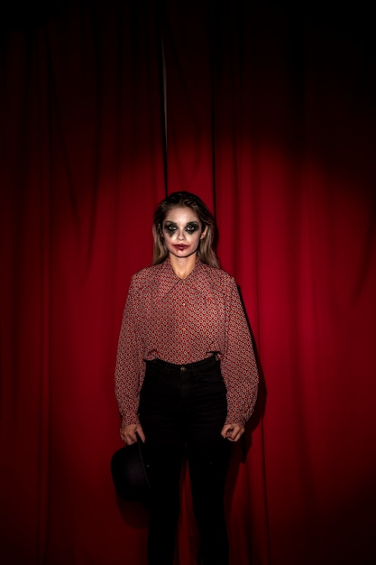 Free photo woman dressed as a clown standing in front on a curtain