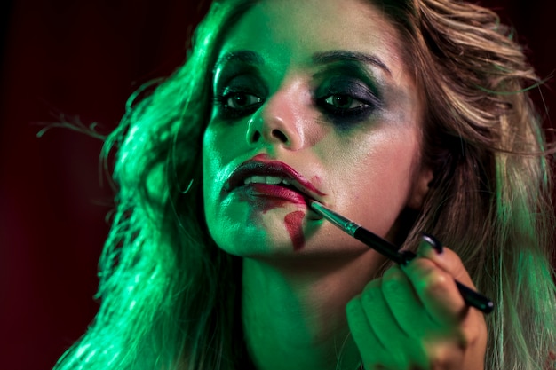 Free photo woman dressed as joker using a brush