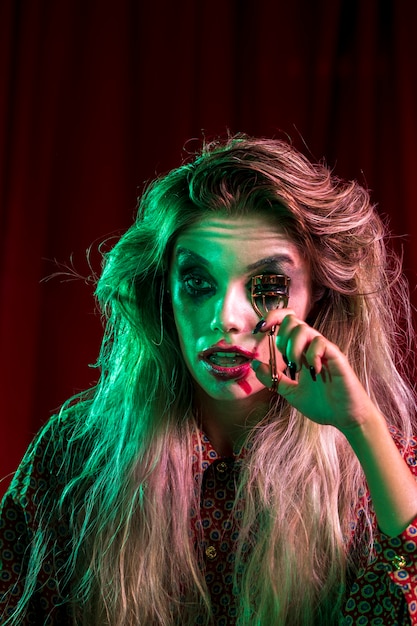 Woman dressed as joker using a eyelash curler