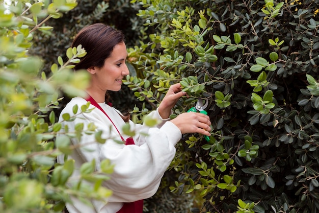 Free photo woman dressed in gardening clothes trimming hedge